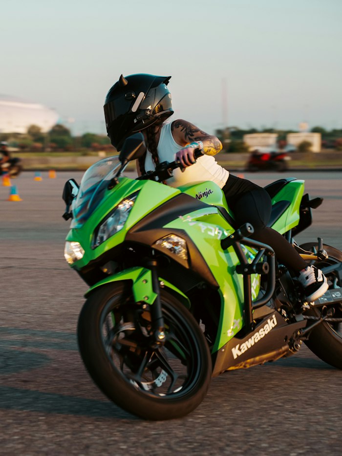 Élève à moto sur le plateau, casque intégral, plots orange en arrière-plan